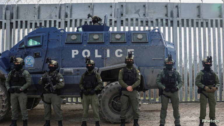Greek police officers line up next to a border fence to prevent migrant crossings, during a press tour at the Greek-Turkish border