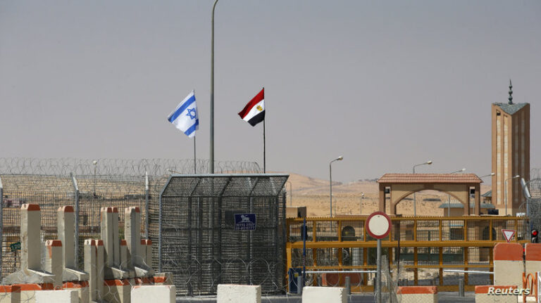 An Israeli flag flutters next to an Egyptian one at the Nitzana crossing, along Israel's border with Egypt's Sinai desert, as seen from the Israeli side