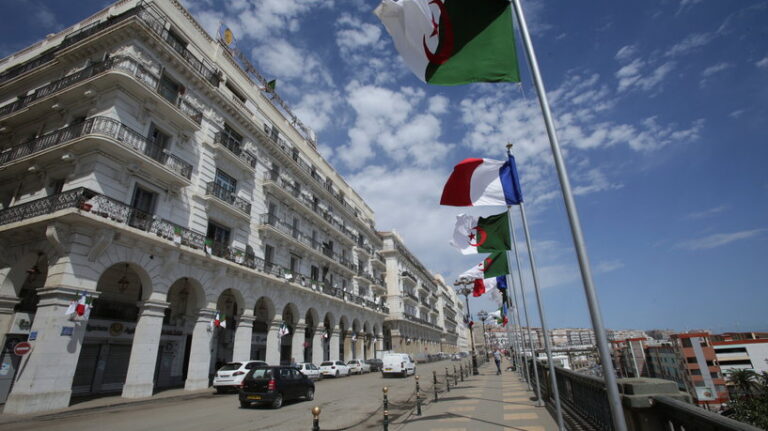 Vehicles pass Algerian and French flags, ahead of the arrival of French President Emmanuel Macron in Algiers